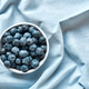 Fresh organic blueberries. Juicy ripe bilberry in white bowl on blue cloth.  - PhotoDune Item for Sale