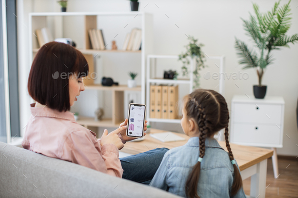 Females surfing e-commerce fashion boutique on smartphone - Stock Photo - Images