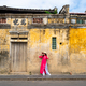 Young female tourist in Vietnamese traditional dress walking at Hoi An Ancient town in Vietnam - PhotoDune Item for Sale