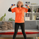 Full length shot of middle aged woman exercising with dumbbells at home. - PhotoDune Item for Sale
