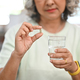 Middle aged woman holding pill and glass of water. Elderly healthcare concept. - PhotoDune Item for Sale