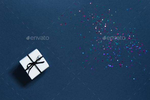 Festive blue background with sparkles and a small white gift box.