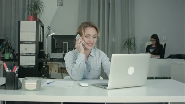 Two Female Coworkers Working Together Answering Phone Calls in the Office