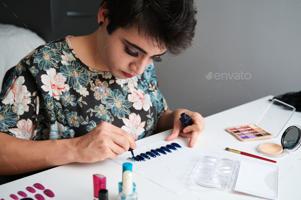 Young drag queen painting false nails.