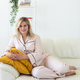 Cute female model in pajama enjoying morning. Pleasant woman sitting on sofa. Good mood - PhotoDune Item for Sale