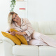 Carefree young woman in cozy pajamas resting on sofa at home - wellbeing and comfort morning concept - PhotoDune Item for Sale