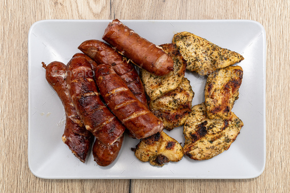 Baked sausage and chicken fillets on a traditional grill, lying on a plate. - Stock Photo - Images