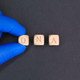 fingers holding a wooden cube with DNA letters. - PhotoDune Item for Sale