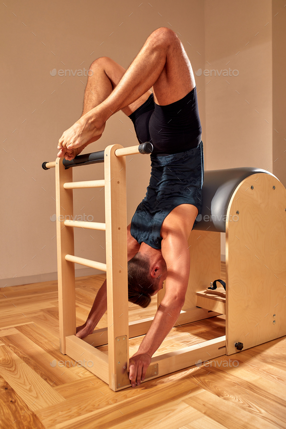 Handsome pilates male instructor performing stretching balance