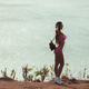 side view of attractive girl in headphones and pink bikini standing on coastline - PhotoDune Item for Sale
