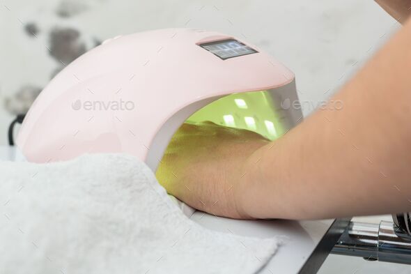 Woman getting a manicure for personal nail care with pink led nail lamp
