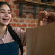 Friendly young indian woman waitress barista giving takeaway food bag to customer female seller cafe - PhotoDune Item for Sale