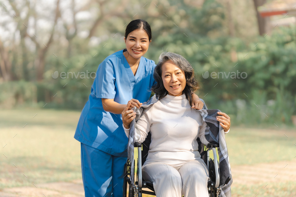 Young asian care helper with asia elderly woman on wheelchair relax together park outdoors to help