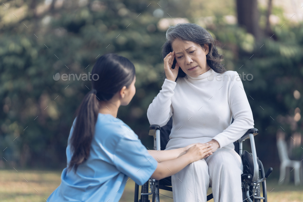 Young asian care helper with asia elderly woman on wheelchair relax together park outdoors to help a