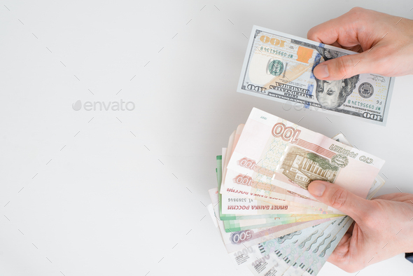 Top view human hands holding rubles and one hundred dollars, close-up. Financial crisis