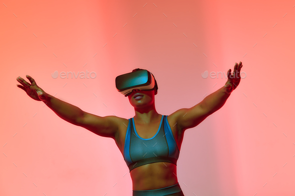 African american woman streamer playing video game using virtual reality glasses at gaming room