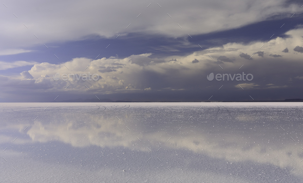 Stormy sky and reflections of clouds in shallow water of Salar de Uyuni - Altiplano, Bolivia - Stock Photo - Images