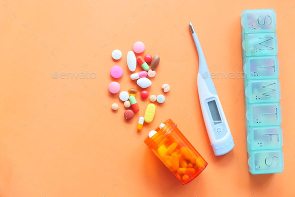  digital thermometer , pill box and pills on orange background  - Stock Photo - Images