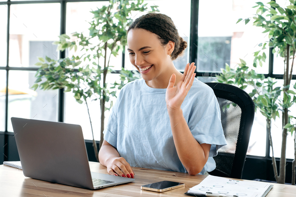 Positive beautiful successful brazilian or latino woman, sits at a desk in the  office, talking on Stock Photo by thelivephotos