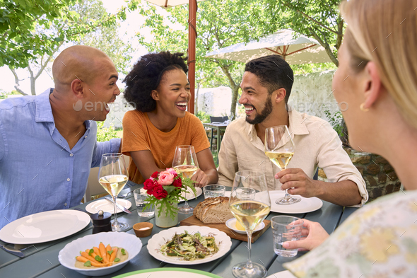Group Of Friends Enjoying Outdoor Meal And Wine On Visit To Vineyard Restaurant - Stock Photo - Images