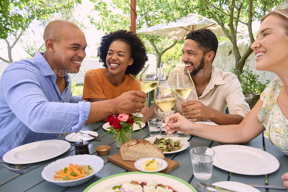 Group Of Friends Enjoying Outdoor Meal And Wine On Visit To Vineyard Restaurant With Cheers - Stock Photo - Images