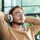 Close-up photo. A young freelancer, a programmer sits in the office wearing white headphones, hands - PhotoDune Item for Sale