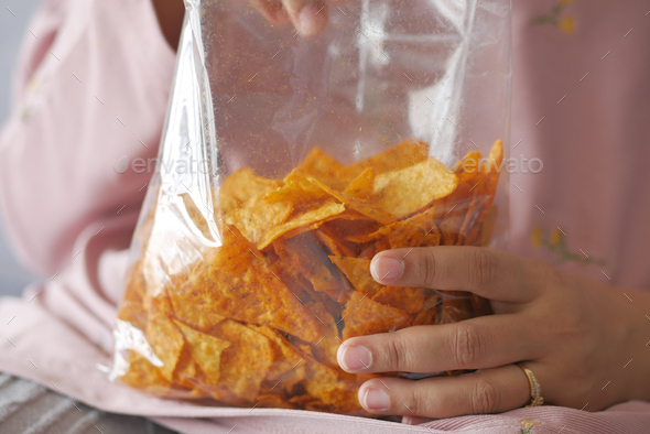 women holding a open potato chips packet  - Stock Photo - Images