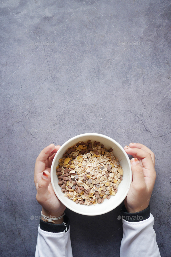  child hand holding a bowl of Musli breakfast cereal  - Stock Photo - Images
