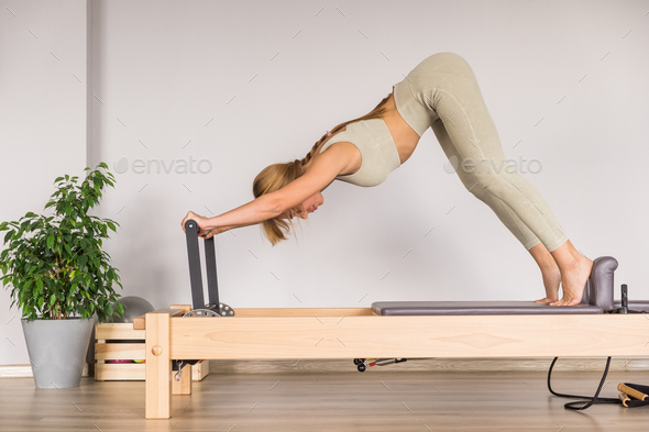 Woman training pilates on the reformer bed. Reformer pilates
