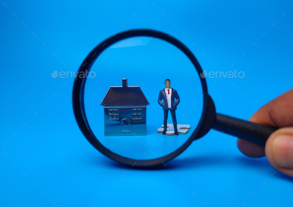 Miniature people,house keychain and magnifying glass on blue background. Real estate concept. - Stock Photo - Images