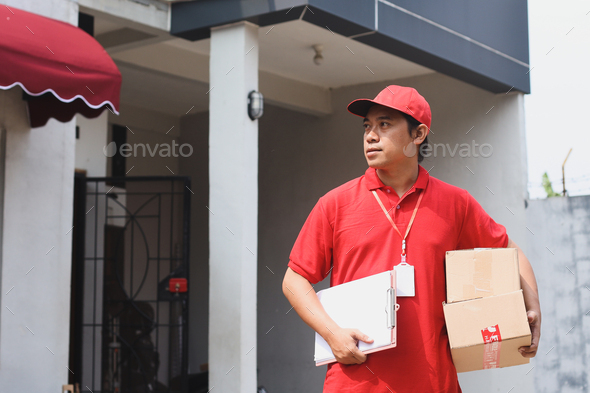 Delivery man holding stack of cardboard and document outdoor