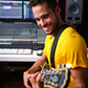 Smiling man sitting playing guitar in recording studio. - PhotoDune Item for Sale
