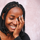 Portrait on a brown background of Afro woman laughing, eyes closed and one hand on her face. - PhotoDune Item for Sale