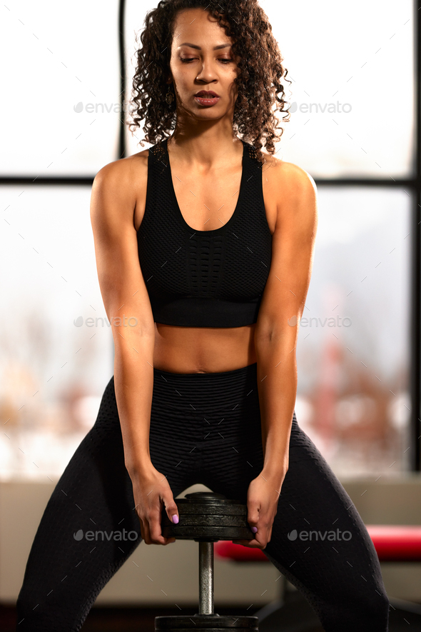 African woman with a healthy slim body and a flat stomach in a black tracksuit close-up training
