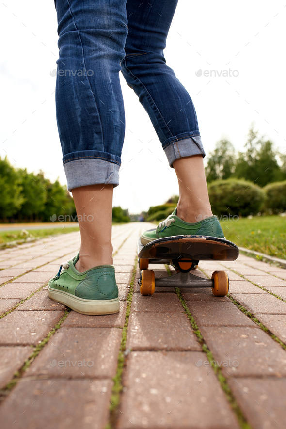 Feet on a skateboard board, rear view shot of feet with sneakers