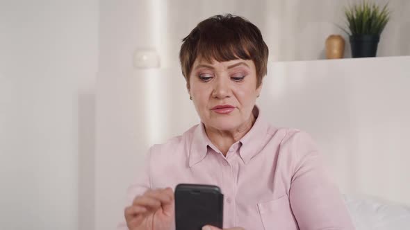 Middle Aged Woman Using Phone for Online Chat