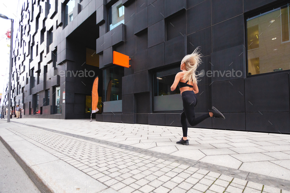 Sporty young woman running fast in minimalist urban environment - Stock Photo - Images