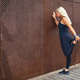 Back view of fit woman stretching after workout against metal wall in the city - PhotoDune Item for Sale