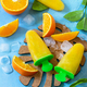 Homemade popsicles with orange juice, fruit ice on a blue stone or slate background. Copy space. - PhotoDune Item for Sale