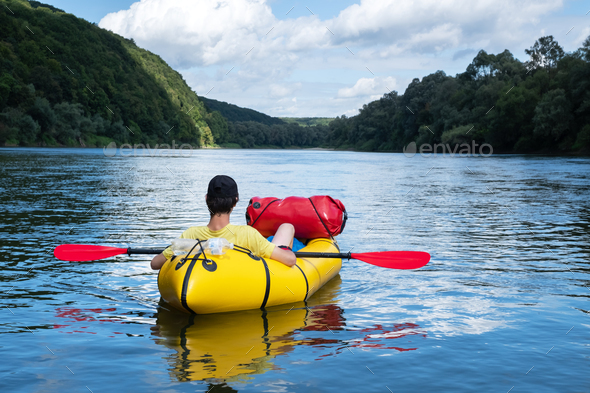 Tourist on yellow packraft rubber boat with red padle - Stock Photo - Images