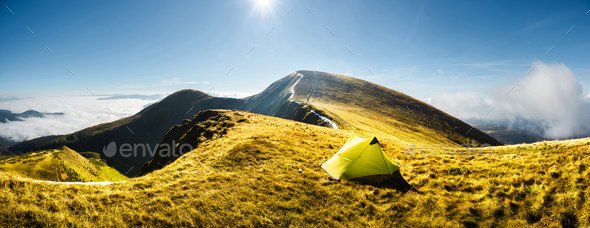 Lonely yellow tent against the backdrop of an incredible mountains - Stock Photo - Images