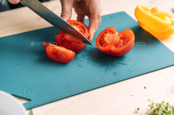 Woman cutting tomato for vegetable salad with microgreens - Stock Photo - Images