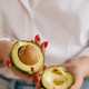 Close-up of a girl&#39;s hand holding an avocado cut in two - PhotoDune Item for Sale