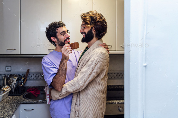 male couple hugging while having morning coffee - Stock Photo - Images