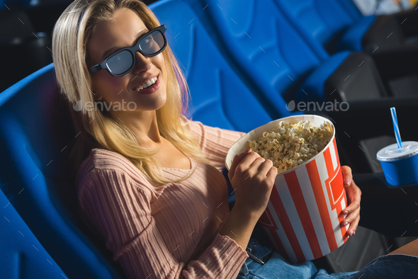 young woman in 3d glasses with popcorn watching film alone in cinema
