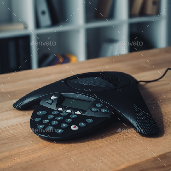 speakerphone on wooden table at office with blurred bookshelves on background - Stock Photo - Images
