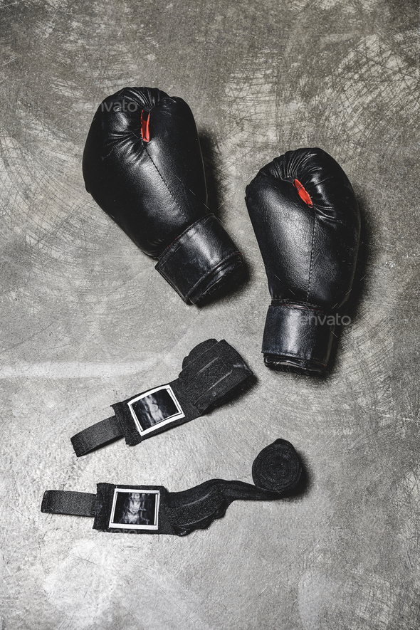 top view of boxing gloves with wrist wraps lying on concrete surface