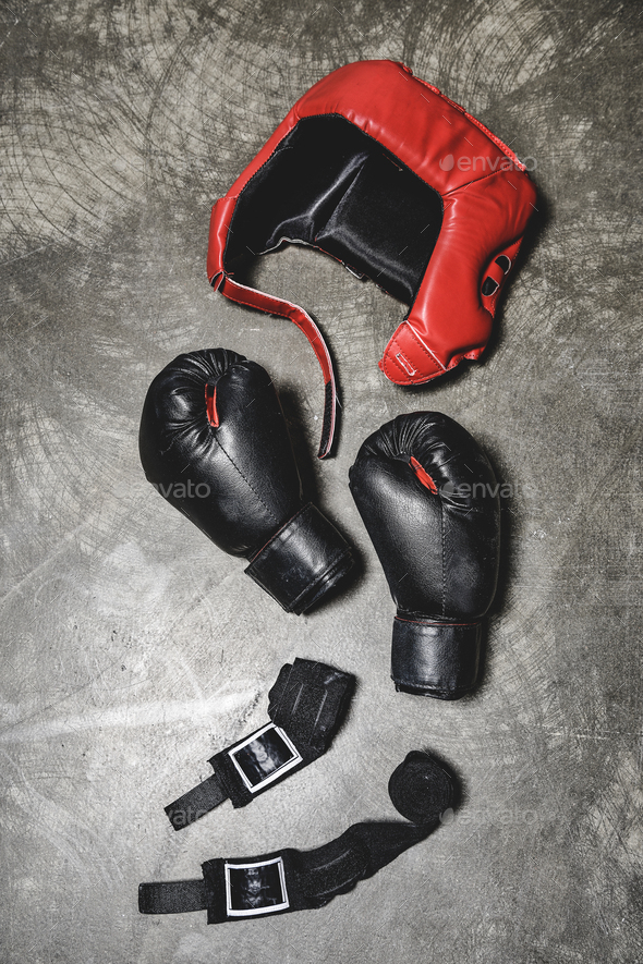 top view of boxing gloves and helmet with wrist wraps lying on concrete surface