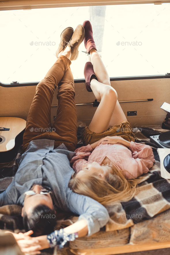 hippie couple resting inside campervan with guitar and vinyl player
