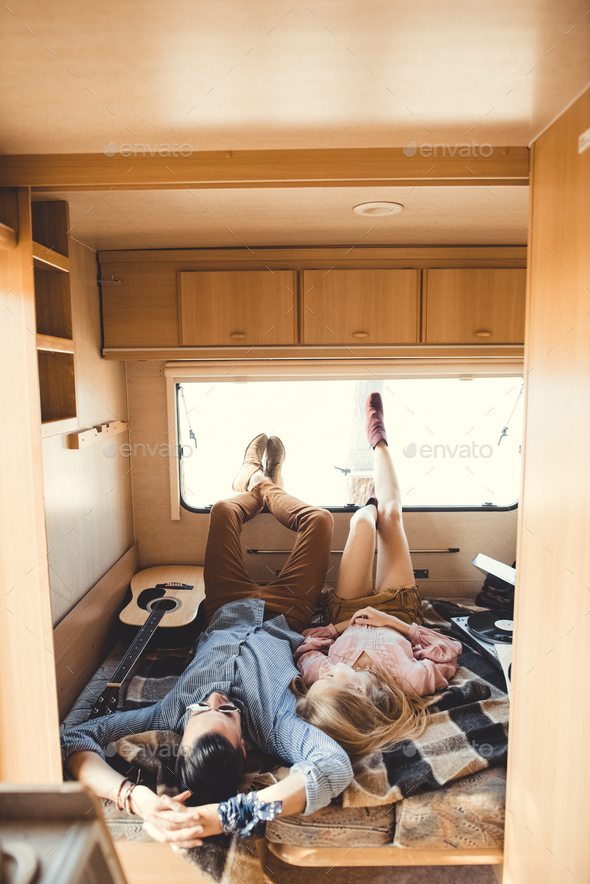 young hippie couple resting inside trailer with guitar and vinyl player